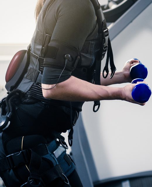 Closeup photo of woman in EMS suit exercising with dumbbells